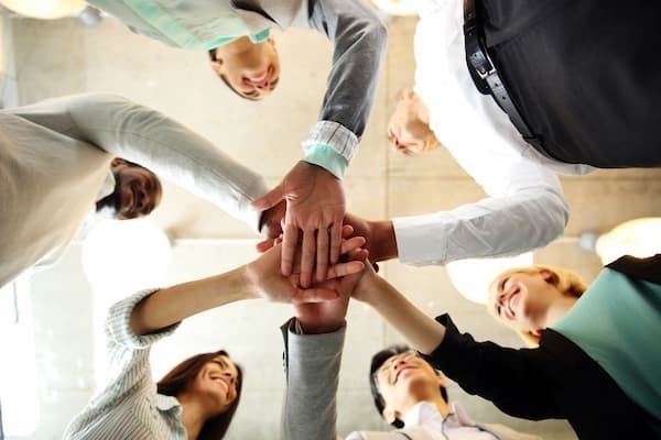 Team Of Business People In A Huddle With Hands In